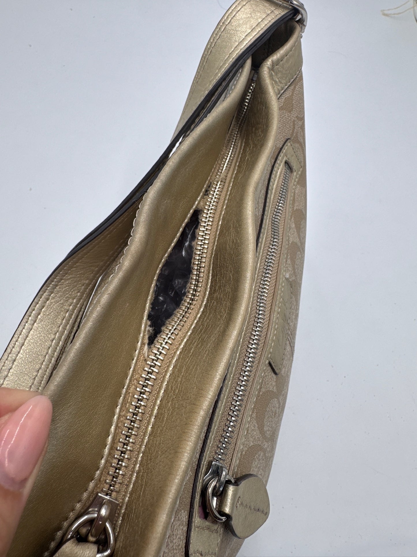 Detailaufnahme der Coach Shoulder Bag, zeigt Struktur und Material in Gold.