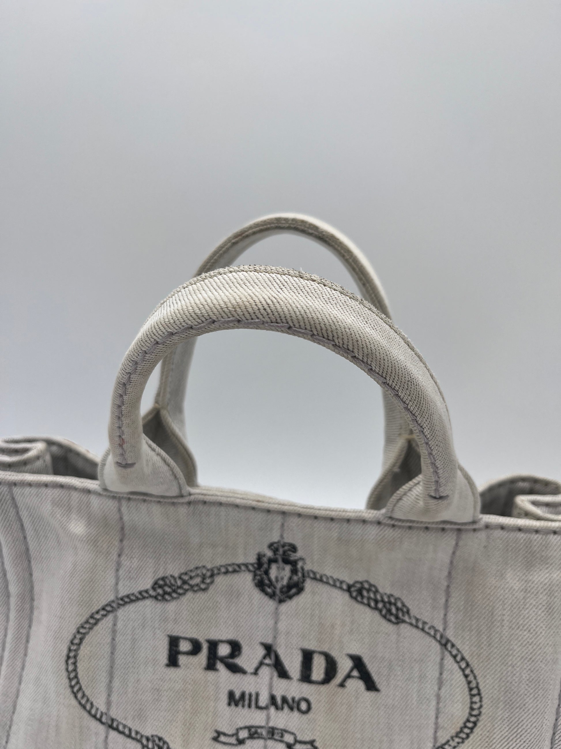 Tragegriffe dieser beige / creme Prada Canapa in Crossbody-Form.